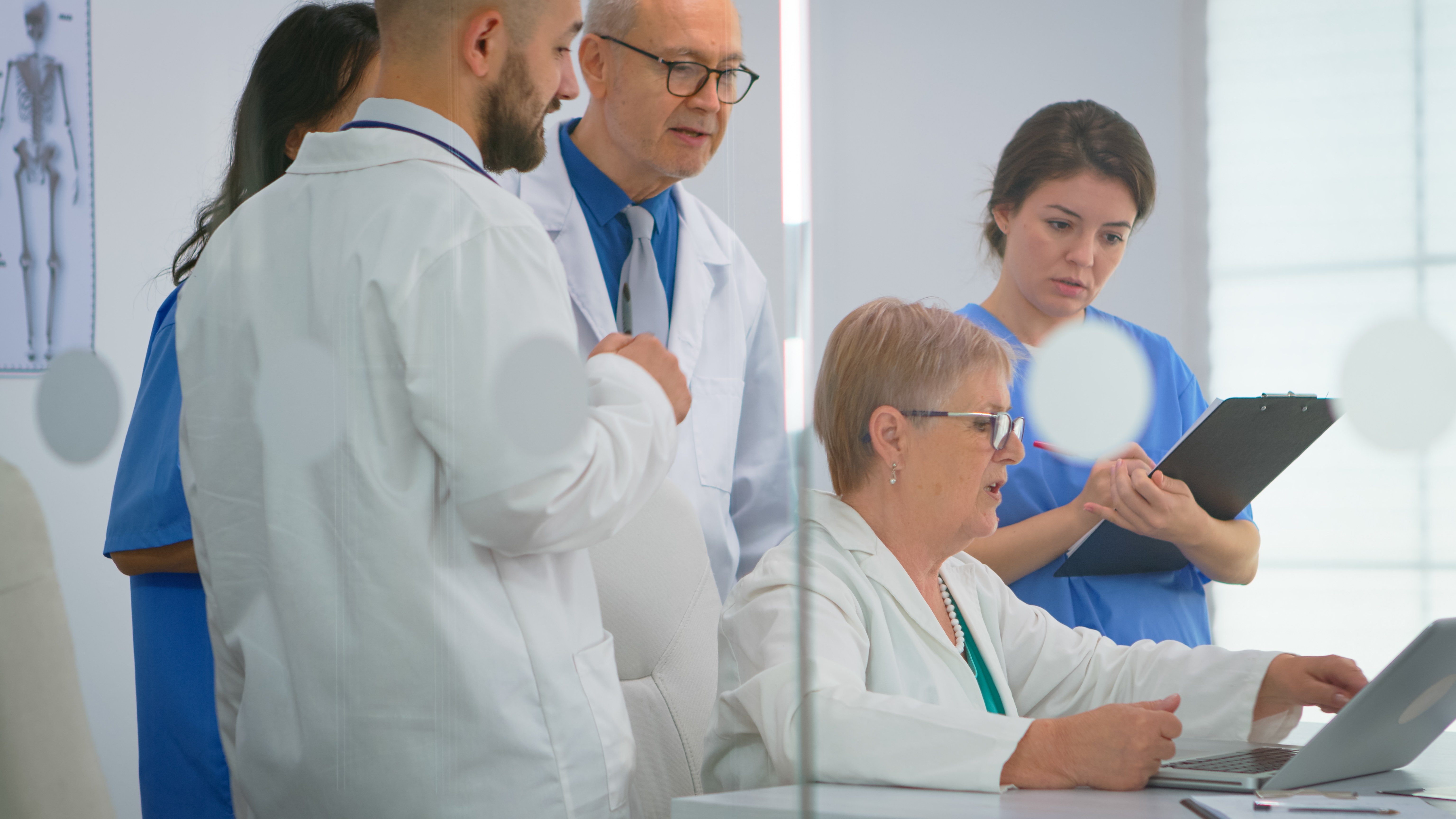 Team of doctors discussing a case around a laptop